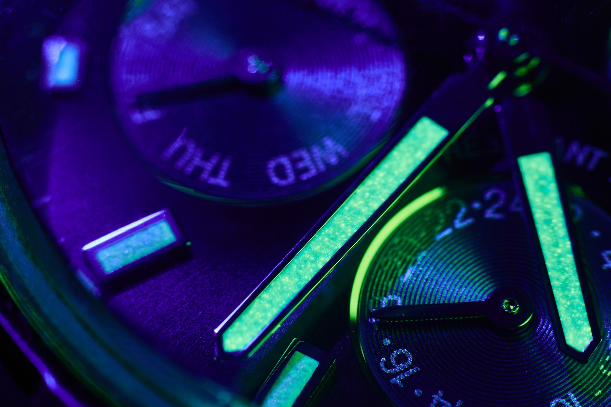 Watch dial and hands glowing under ultraviolet light with luminous green details