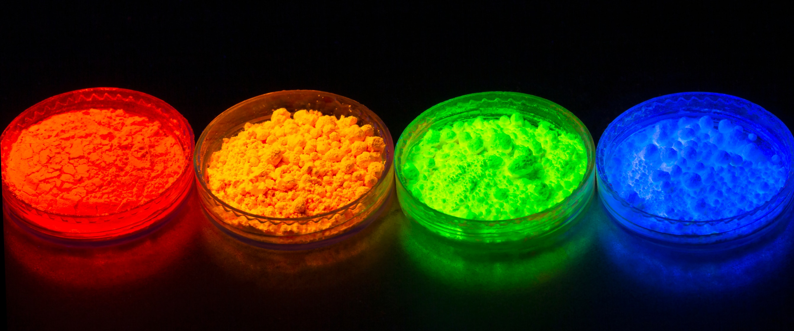 Fluorescent organic materials powder of red, yellow, green color for production OLED displays in UV light. Closeup.