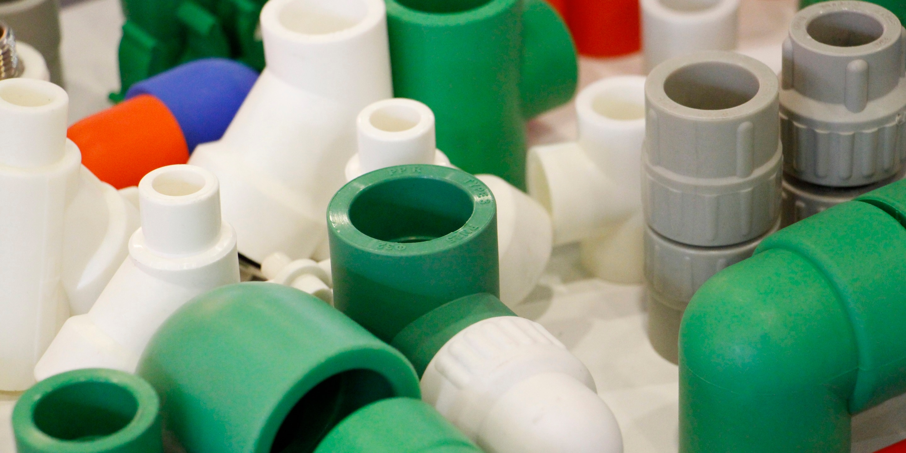 Plastic products used for industry. Many colored plugs, screws, valves, fittings, pipes, plastic adapters. Manufacture of plastic products. The concept of plastic products.